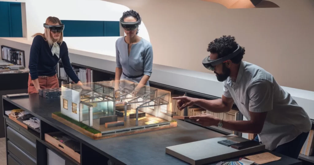 Two women and one man looking at a 3D holographic building.