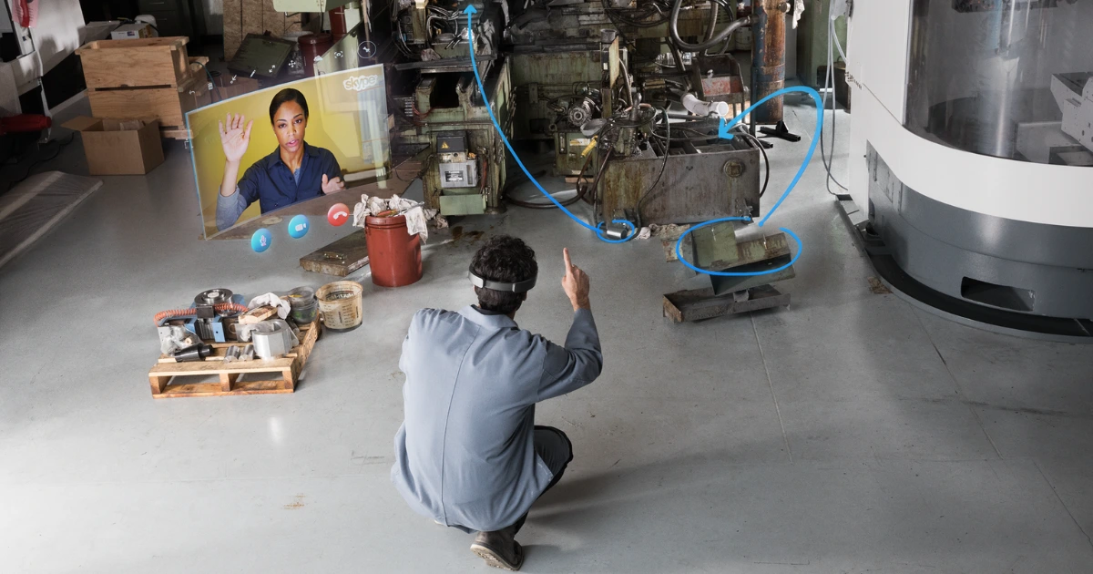 A HoloLens-wearing technician communicating with his co-worker through Skype, while drawing virtual arrows on the machines.